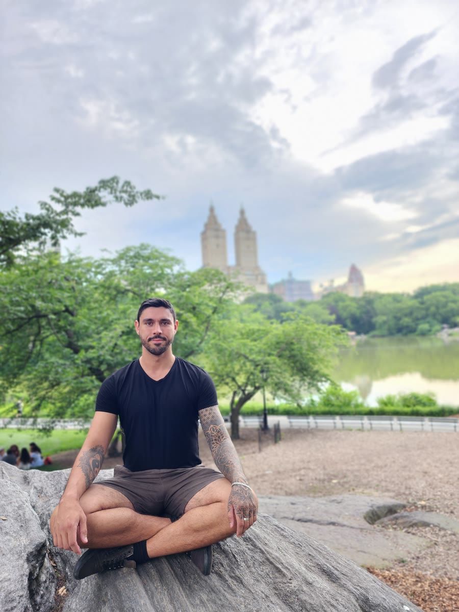 Devin sitting cross-legged on a rock in Central Park